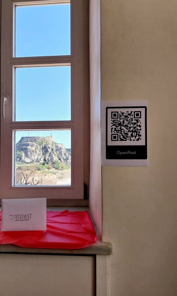 QR code της OpenPast δίπλα σε παράθυρο με θέα στο φρούριο της Κέρκυρας.